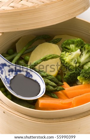 Assorted steamed vegetables in a bamboo steamer. Served with soy sauce. Selective focus.