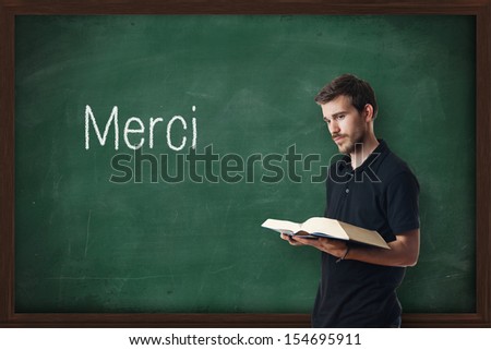 Young professor of French writing Merci on chalkboard