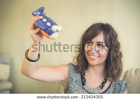 Smiling woman playing with a toy airplane as she daydreams about an upcoming summer vacation and flying to new destinations