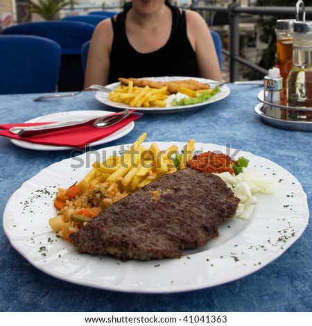 photo of a couple eating french fries and a steak at a restaurant