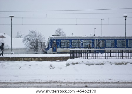 Train pulling into a station with heavy snow falling