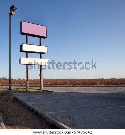 Blank signs in an empty parking lot, with an empty field and trash in the background