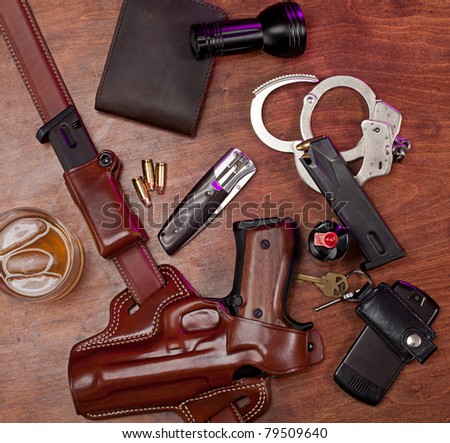 Equipment typically carried by a law enforcement officer, on a wooden table with a glass of whiskey.
