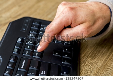 finger about to press the delete button on a keyboard.
