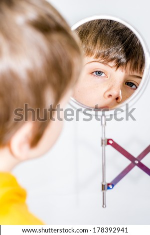 little boy looking in a vanity mirror