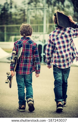 two skater boys walking towards half pipe,vintage effect added