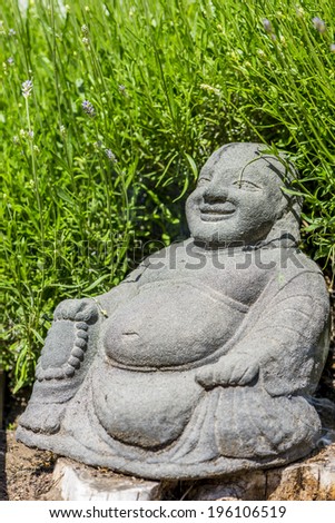 laughing buddha statue, in front of lavender bush