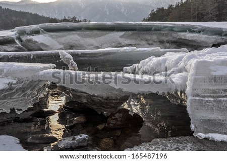 Winter landscape with mountain river and blocks of ice on a sunny winter day.