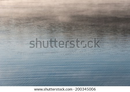 Abstract textured background of ripples on the water and mist in the background