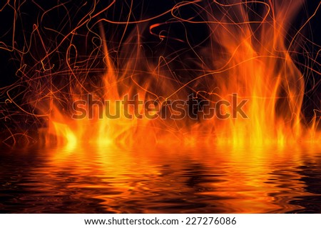 Flames of fire and sparks on a black background with reflection in water