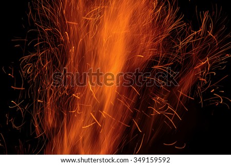 Red and orange fire background of flame and sparks from the bonfire in the form of tracks on a black background