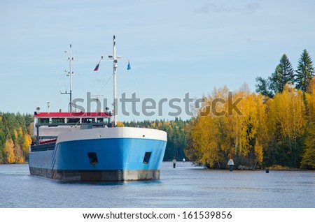 Cargo ship moving down the river autumn morning