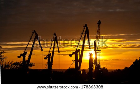 silhouette of harbor cranes on sunset sky background