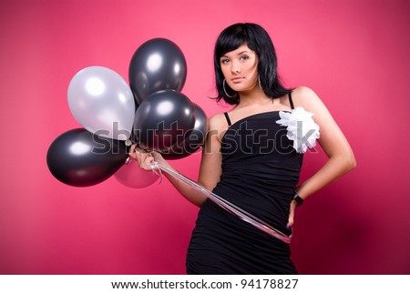 Photo of a young girl with a black and white balloons on a pink background