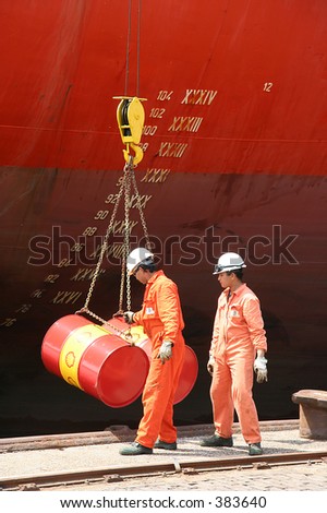 Industrial scene : 2 sailors loading drums into ship