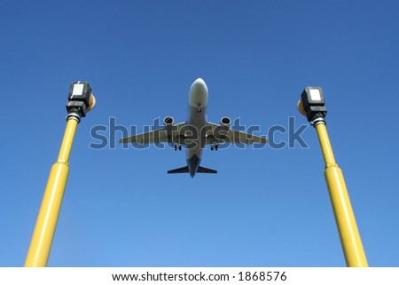 A landing airplane framed between two airport guide light poles