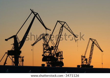 Silhouettes of cranes in a port at dusk