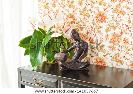 Side table with flowers and interior decoration next to bright window