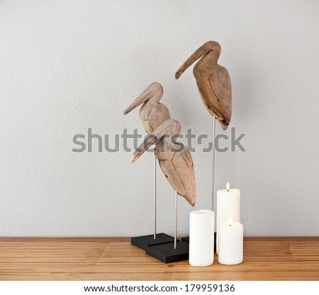 Three wooden birds and candles on a side board