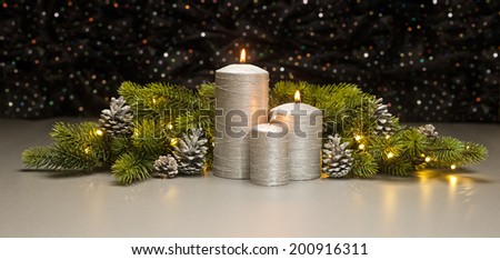 Three Silver Candles with Christmas tree branches and pine cones decorated