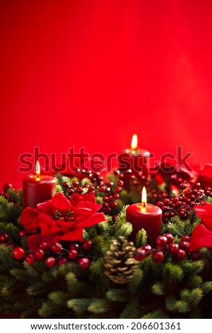 Advent wreath over red background with winter rose and berries