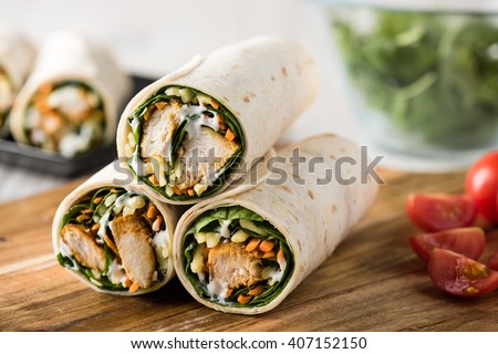Fresh healthy chargrilled tandoori chicken wrap with tzatziki, cheese, baby spinach and carrots
