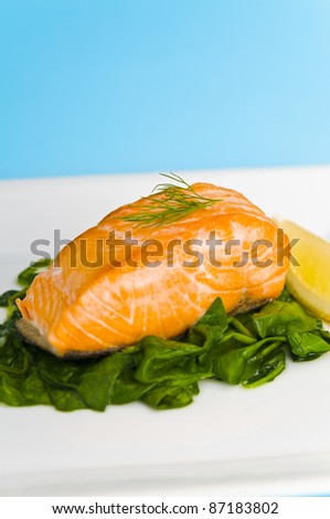 Salmon steak on spinach, decorated with lemon and dill