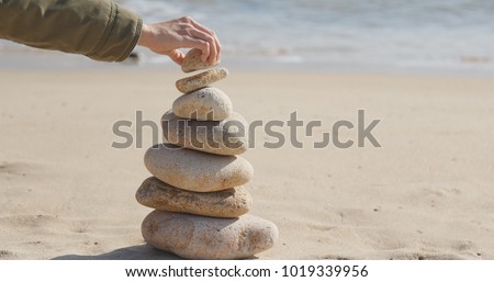 Hand putting the pebble stone on balance zen stock
