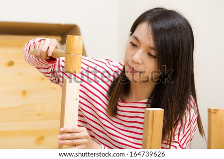 Asian woman using hammer for assembling