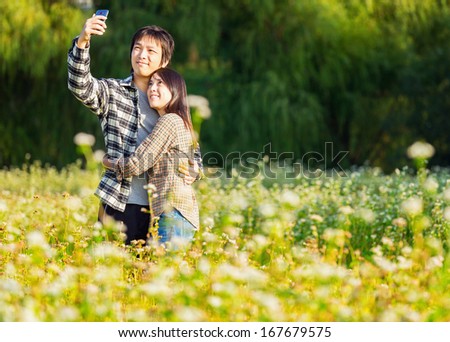 Asian couple take photo by mobile phone