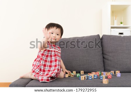 Asia baby girl play toy block and sitting on sofa