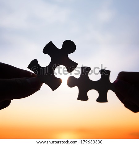 Two hands trying to connect puzzle pieces