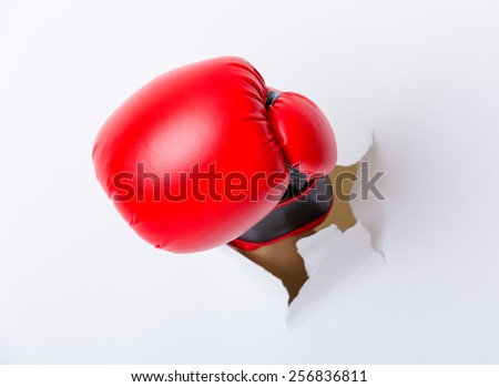Punching boxing glove though over paper wall