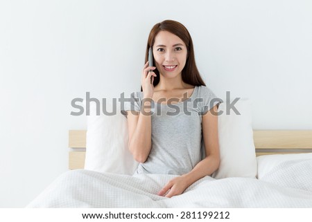 Woman talk to mobile and sitting on bed