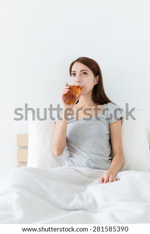 Young woman drinking a cup of tea on bed