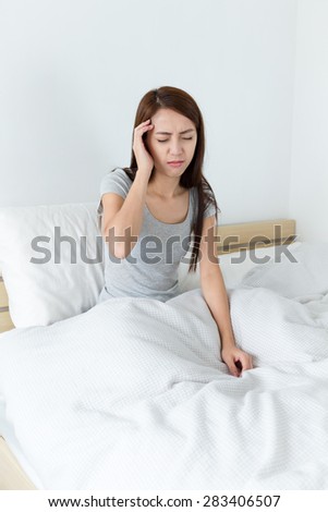 Woman got headache and sitting on bed