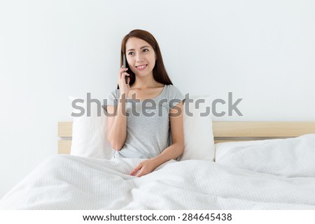 Woman talk to cellphone and sitting on bed