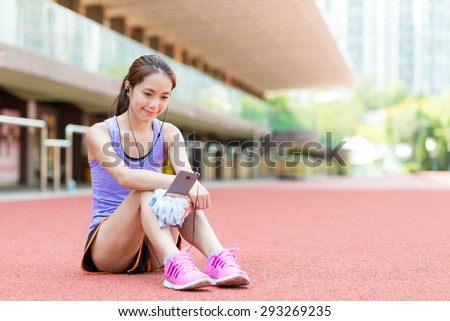 Woman sitting on stadium and listening to music after doing exercise