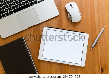 Office table with digital tablet showing a blank screen for advertising