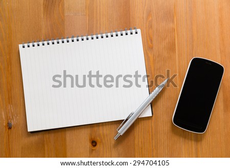 Mobile phone on desk with blank handbook for input something