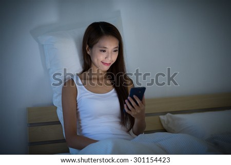 Woman look at the mobile phone on bed