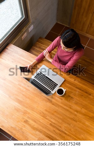 Top view of woman check the email on mobile phone together with notebook computer