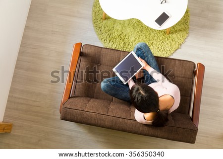 Top view of woman watching on tablet pc and sitting on sofa