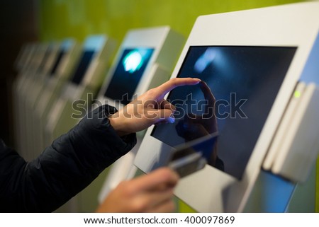 Woman using the self services terminal to pay on the fare