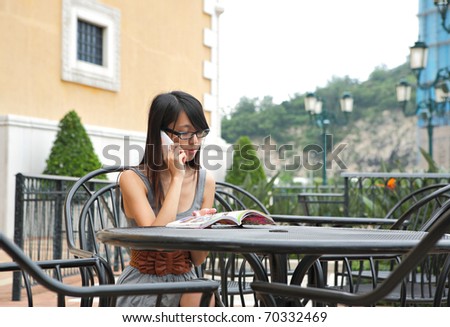 girl read book and talk phone in cafe