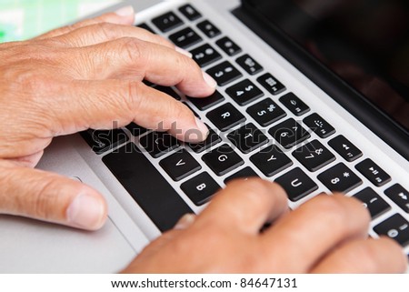 Hands of old man on computer