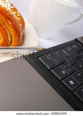 Note book keyboard close up with coffee cup and bakery in the background