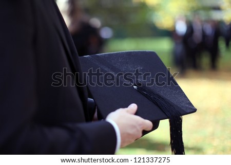 Man holding a mortar board in focus on a autumn day in Oxford