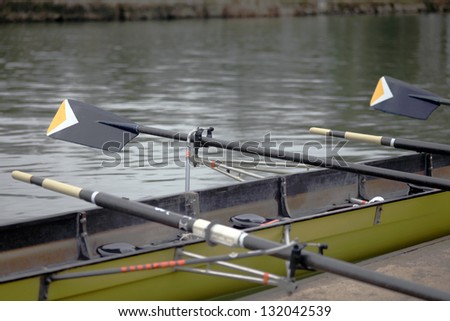 Yellow rowing boat of a Oxford University college with oars out on the river Isis in Oxford