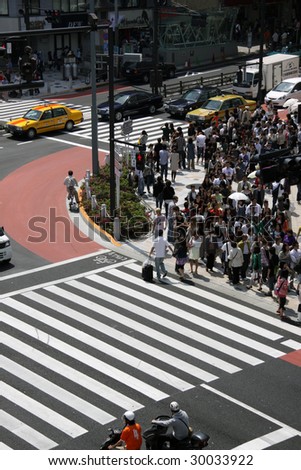TOKYO - MAY 2: Busy people wait at a crossing in Tokyo\'s Omotesando district on May 2, 2009 in Tokyo. Around 100,000 cars drive down the main street of that district daily.